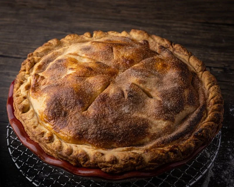 Un pastel de queso entero enfriándose en una rejilla después de salir del horno