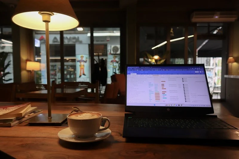 Persona trabajando en laptop en una cafetería acogedora con café y pasteles