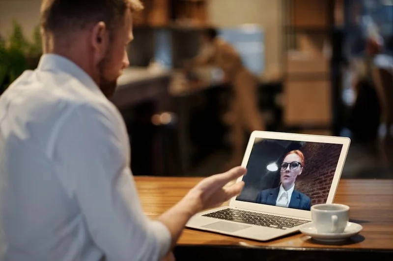 Persona en videollamada en laptop en cafetería moderna y luminosa