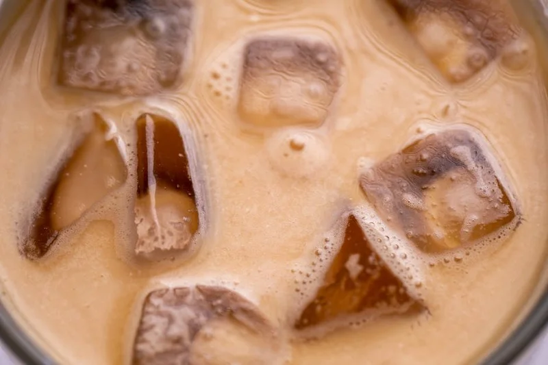 Un primer plano de un café cold brew junto a una vibrante mousse de maracuyá, destacando texturas contrastantes