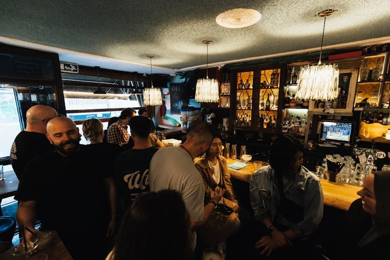 Un animado bar de tapas en Sevilla con gente de pie disfrutando de pequeños platos y bebidas