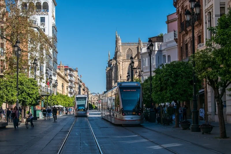 Una animada escena callejera en Sevilla al anochecer con gente disfrutando de tapas al aire libre
